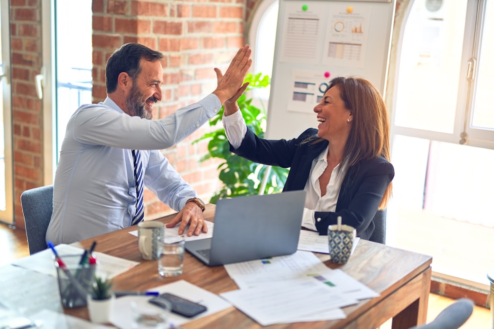 Two people talking warmly across a kitchen table while reviewing paperwork
